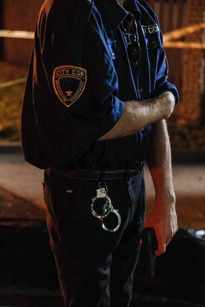 Mastering the First Impression: Your intriguing post title goes here Police officer holding a gun with handcuffs hanging on belt in an outdoor setting.