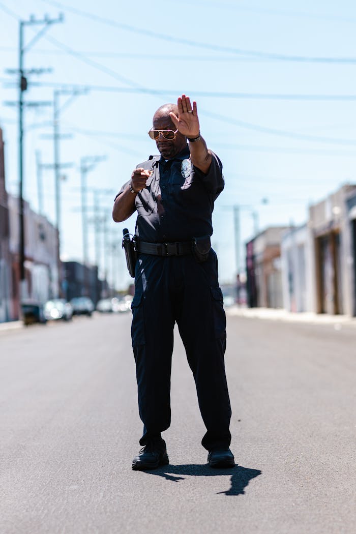 Services Police officer in uniform gesturing stop in a city street during the day.